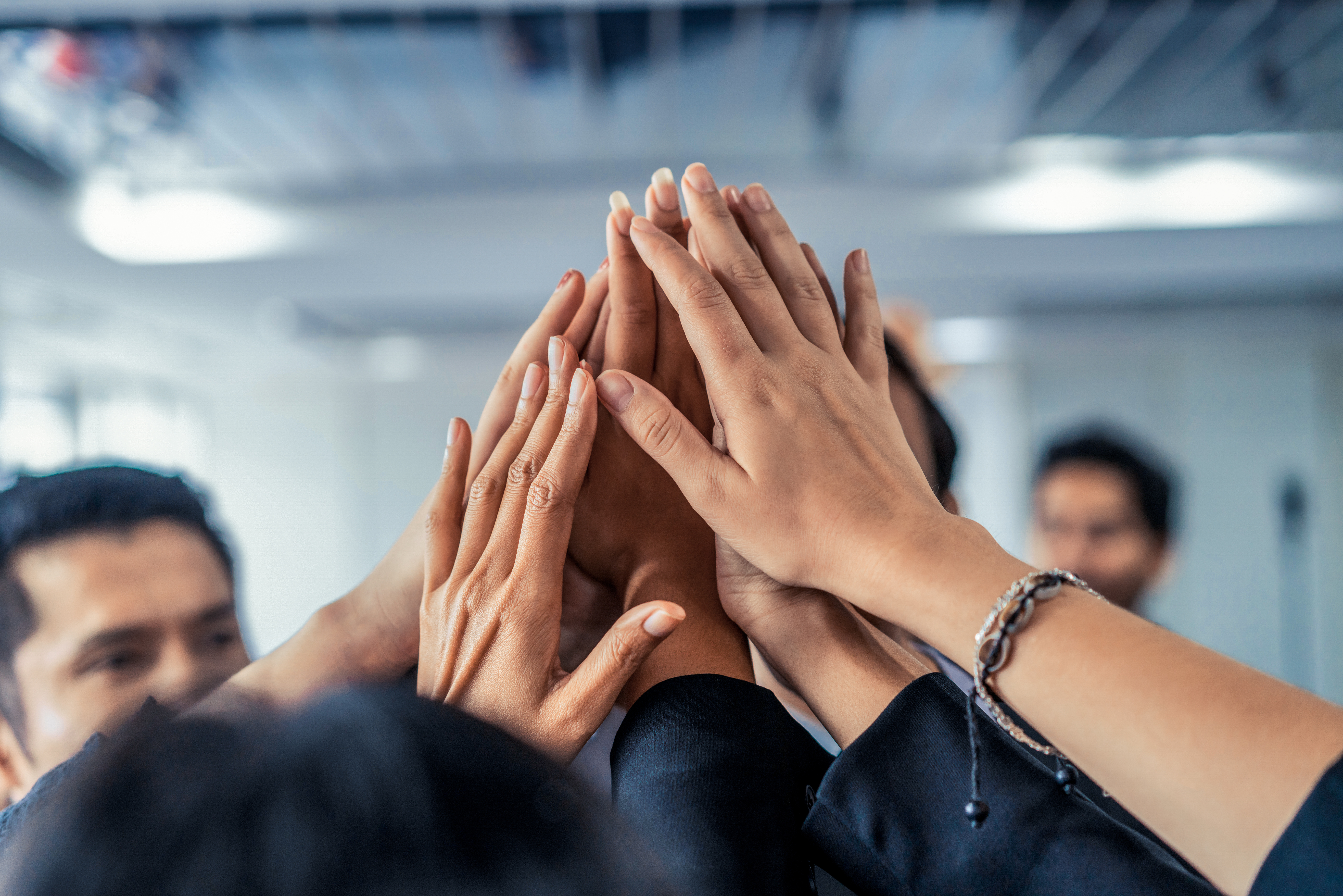 Many happy business people raise hands together.